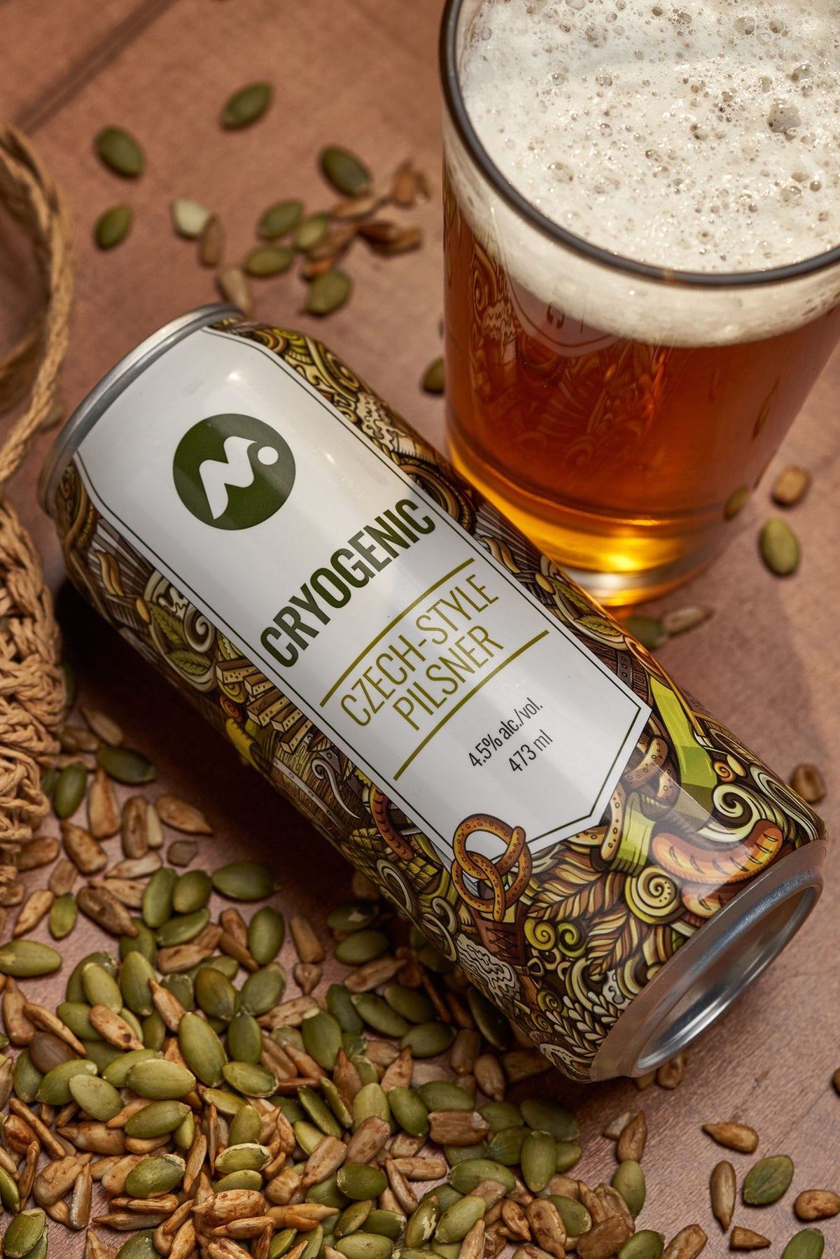 A can of Cryogenic Czech-style Pilsner beside a poured glass and pumpkin seeds