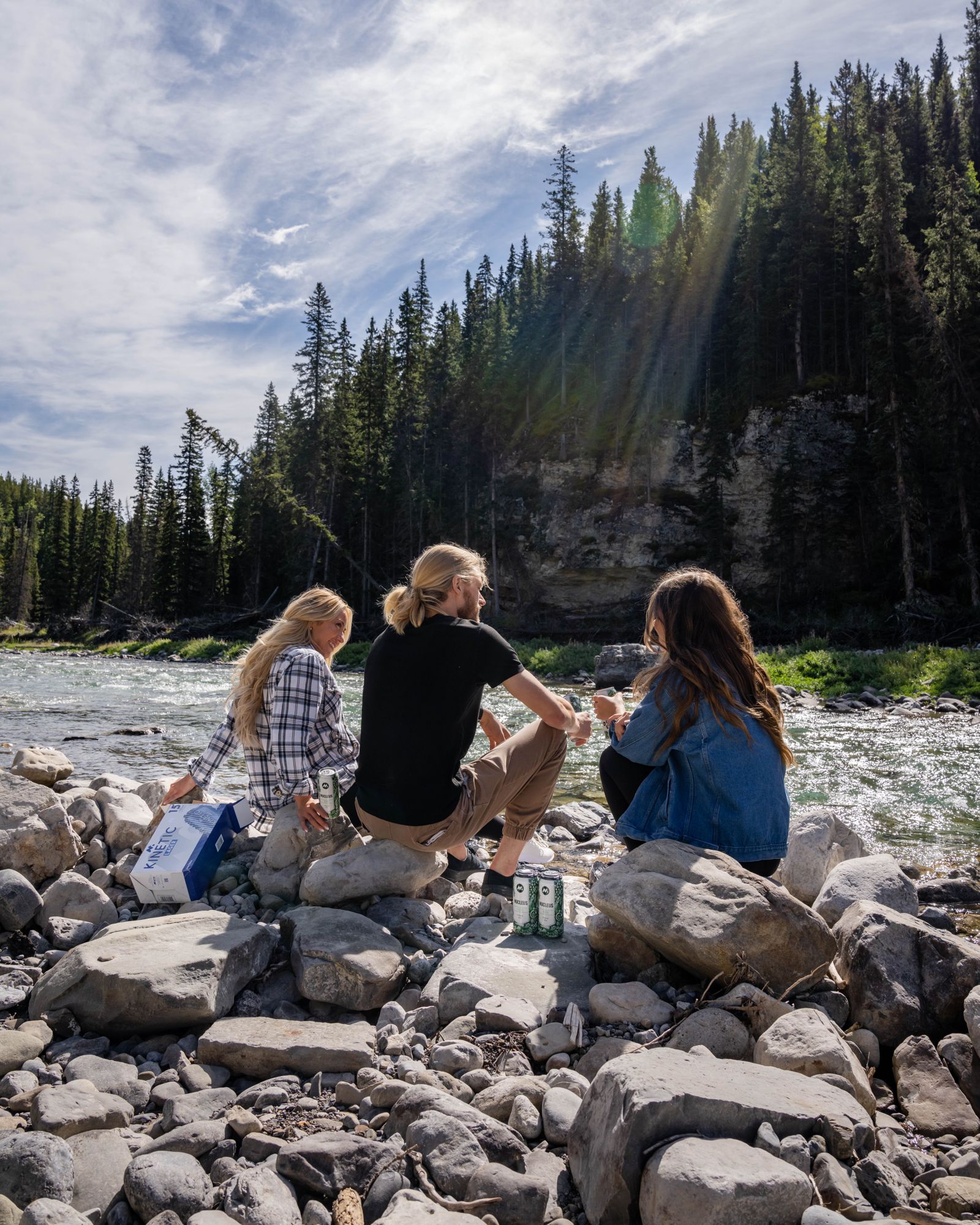 Friends raising Meta beers beside a mountain river